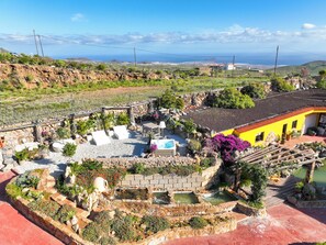 A garden with a pool, a stone wall, and a yellow building. - Finca Ifaya, a private lodging located on a beautiful and peaceful estate (San Miguel)