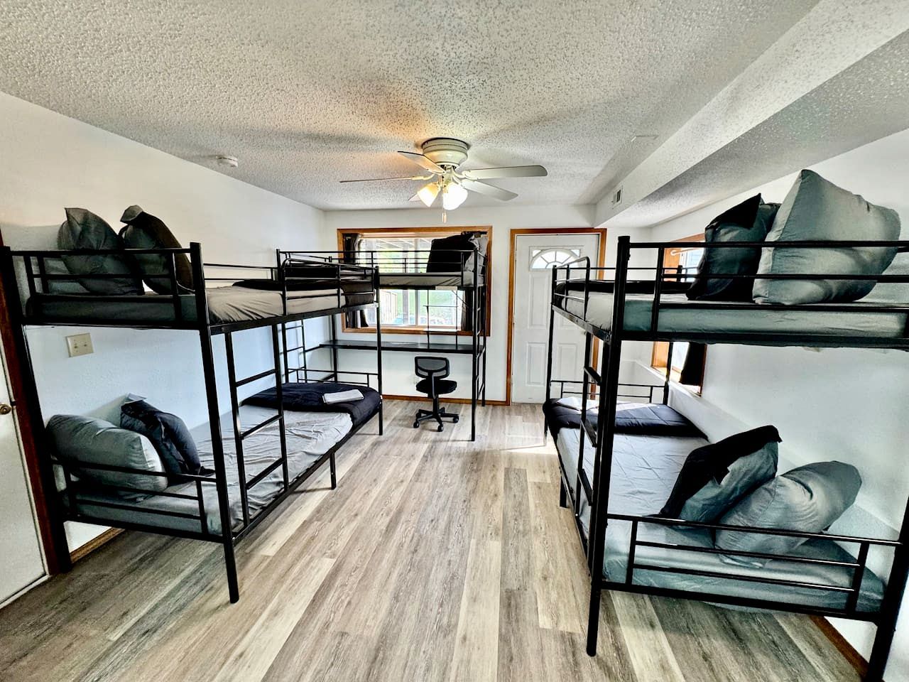 Un dormitorio con literas, ventilador de techo y ventana.