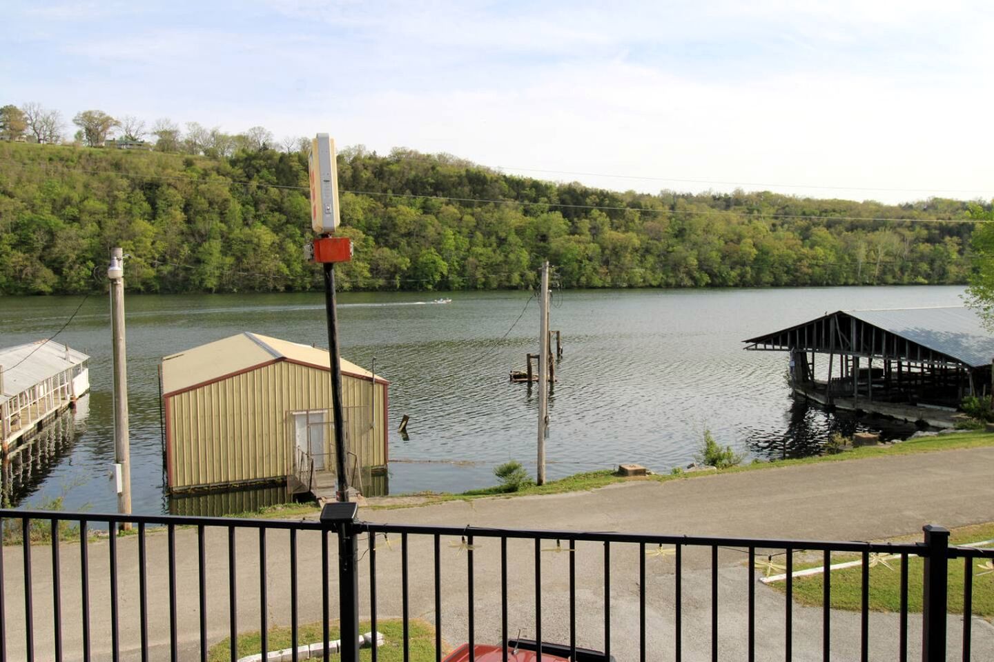 A lakeside dock with a small building, a pier, and a docked boat.