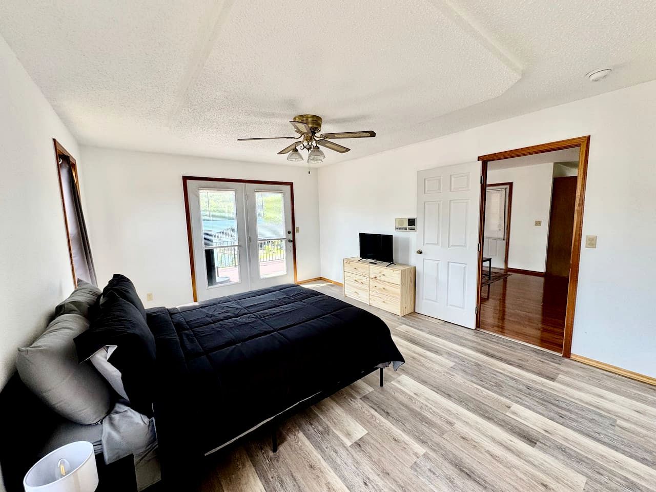 Ein Schlafzimmer mit Bett, Deckenventilator, Fernseher und Kleiderschrank.