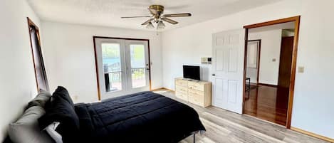 A bedroom with a bed, a ceiling fan, a TV, and a wardrobe.