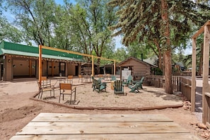 An outdoor seating area with tables and chairs, a wooden deck, and a covered building with a green roof. - Trailside Cabin Escape with Stunning Views and Easy Adventure Access in Colorado Springs, Colorado (Colorado Springs)