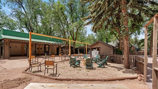 Un espace extérieur aménagé avec des tables et des chaises, une terrasse en bois et un bâtiment couvert doté d’un toit végétalisé.