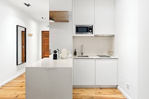 Eine moderne Küche mit weißen Schränken, einer eingebauten Mikrowelle, einer Kaffeemaschine und einem Spülbecken.