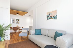 Un salon moderne avec un canapé, des fauteuils, une table à manger et des œuvres d’art accrochées au mur.