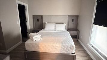 Quarto com cama, ventoinha no teto, janela e porta.