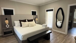 A bedroom with a bed, bedside tables, a ceiling fan, a large mirror, and a window with blinds. - Luxury Designer Home • Disney, Universal & Downtown (Winter Park)