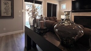 A modern living room with a dark wood floor, a large glass vase, a ceiling fan, and a fireplace. - Luxury Designer Home • Disney, Universal & Downtown (Winter Park)