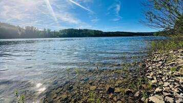 Un lac aux eaux limpides, bordé d’une rive rocheuse et avec des arbres en arrière-plan.