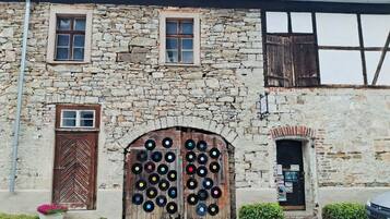Un bâtiment en pierre avec deux portes en bois, une petite fenêtre et une enseigne.