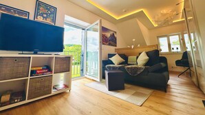A modern living room with a flat-screen TV, a sofa, a coffee table, and a bookshelf.