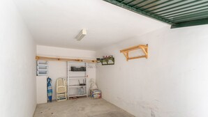 A small, enclosed room with a concrete floor, a white wall, a wooden shelf unit, and a green-framed window. - Vacation Home 'Bellavista Los Pinos' with Mountain Views, Private Terrace and Wi-Fi (Almuñécar)