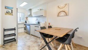 A modern kitchen with a wooden table and chairs, a black chair, a cart, and a window. - Vacation Home 'Bellavista Los Pinos' with Mountain Views, Private Terrace and Wi-Fi (Almuñécar)