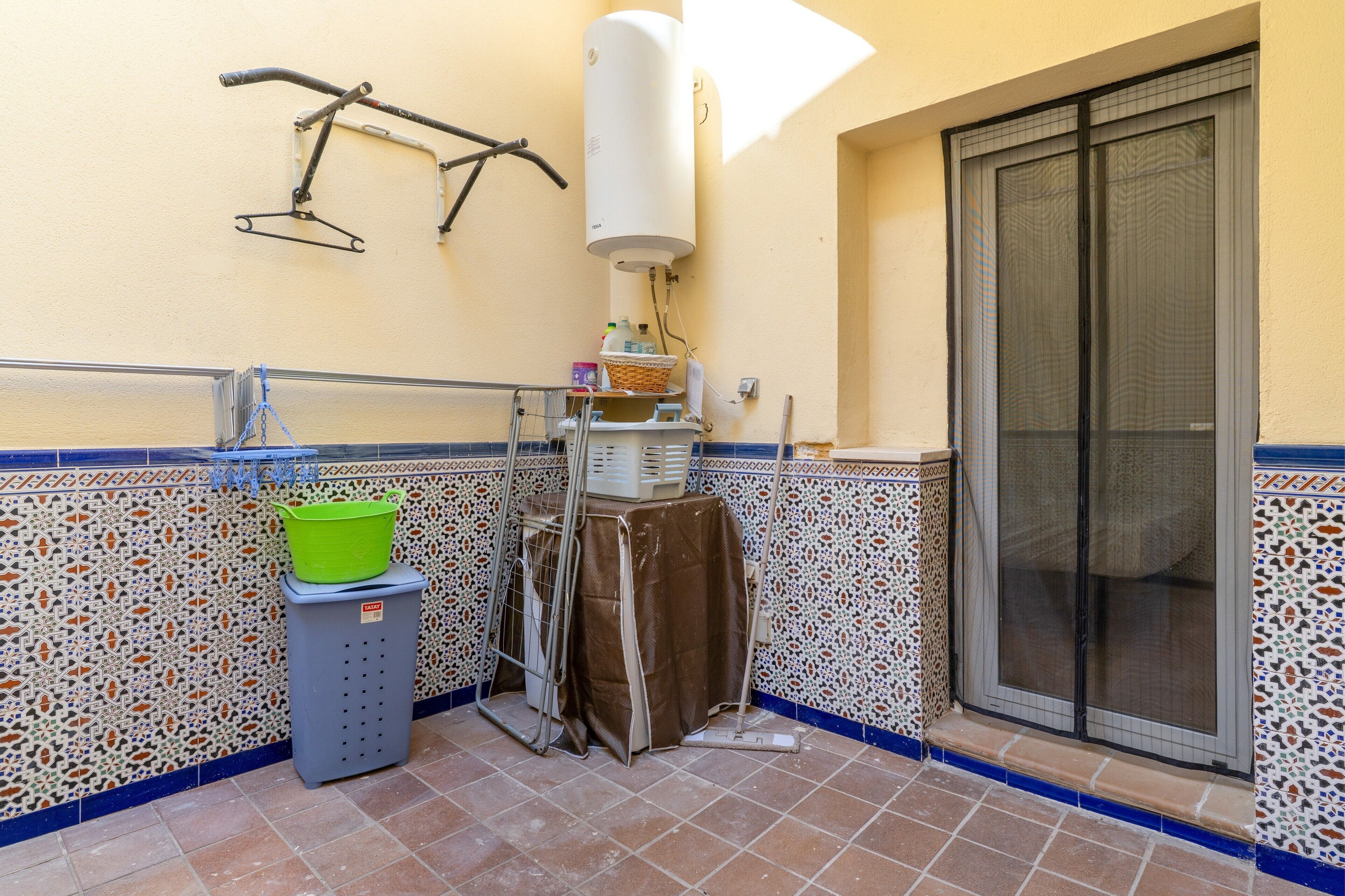 A bathroom with a tiled floor, a towel rack, a shower area, and a water heater.