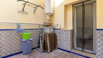 A bathroom with a tiled floor, a towel rack, a shower area, and a water heater.