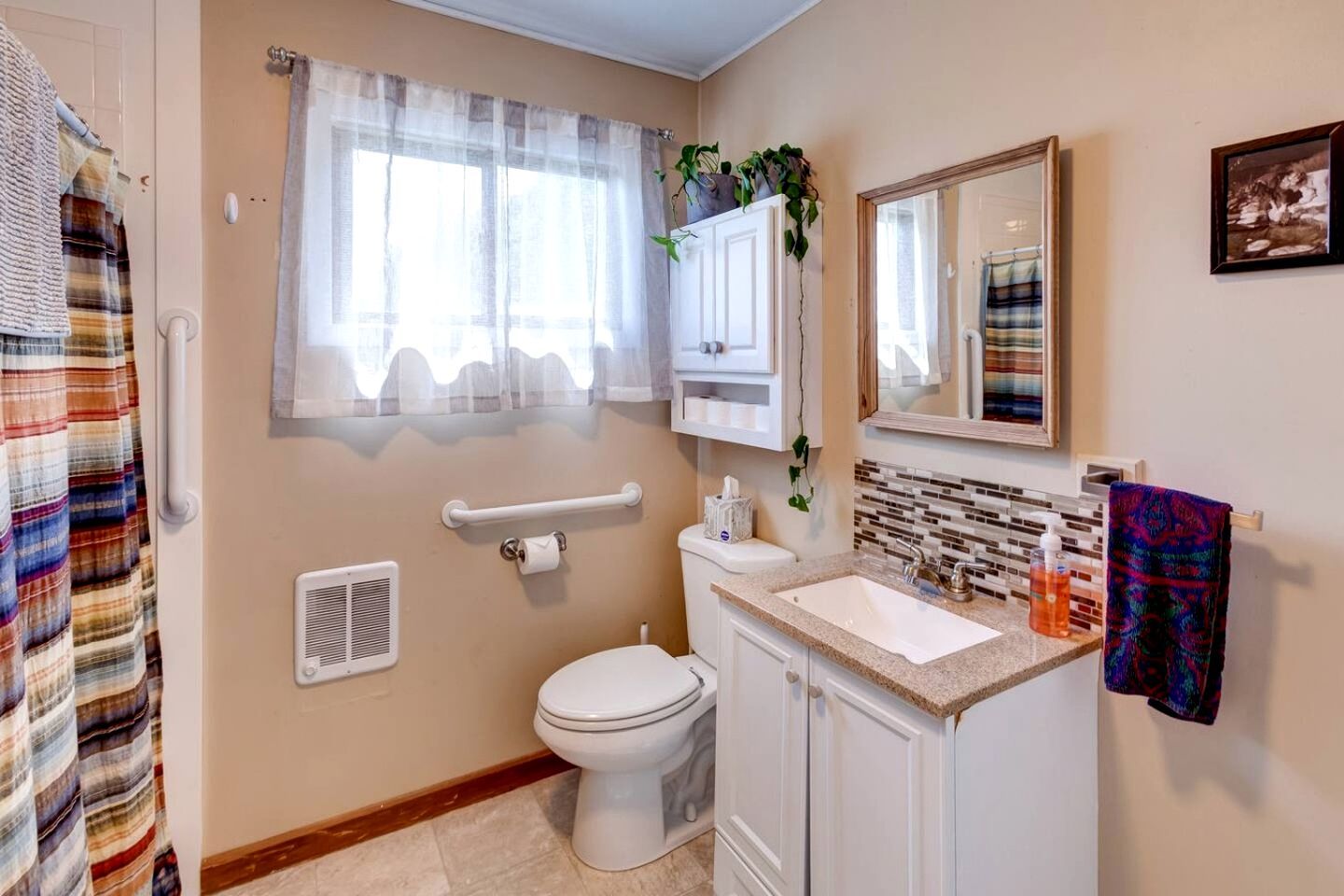 A bathroom with a toilet, sink, and window with curtains.