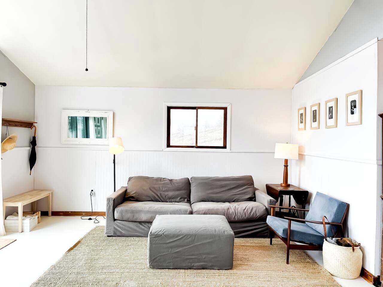 Ein modernes Wohnzimmer mit einem grauen Sofa, einem passenden Ottomanen, einem blauen Sessel, einer Stehlampe und einem kleinen Tisch.