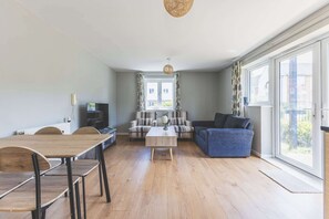 Ein modernes Wohnzimmer mit Essbereich, einer Sofagarnitur und einem Fernseher.