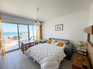 Ein Hotelzimmer mit Bett, Schreibtisch, Stuhl, Tisch, Lampe und einem Bild an der Wand.