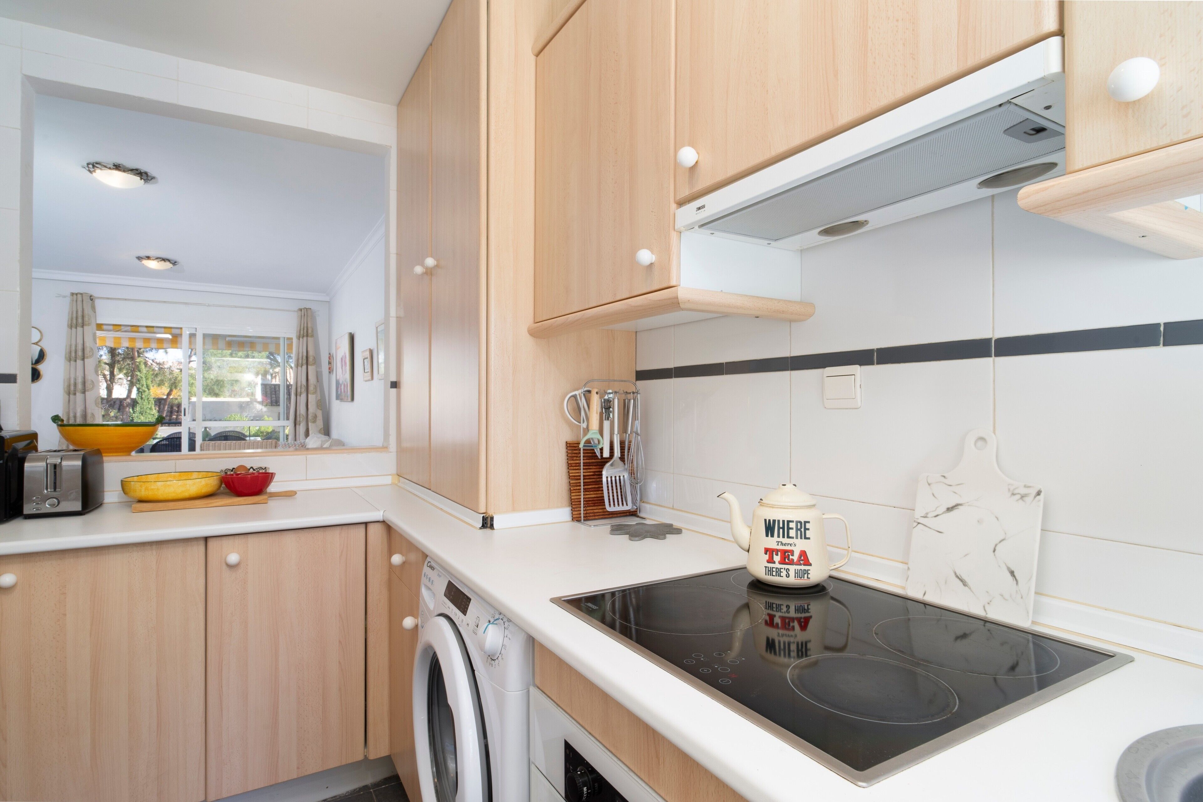Eine moderne Küche mit Holzausstattung, integriertem Backofen und einem Fenster mit Vorhängen.