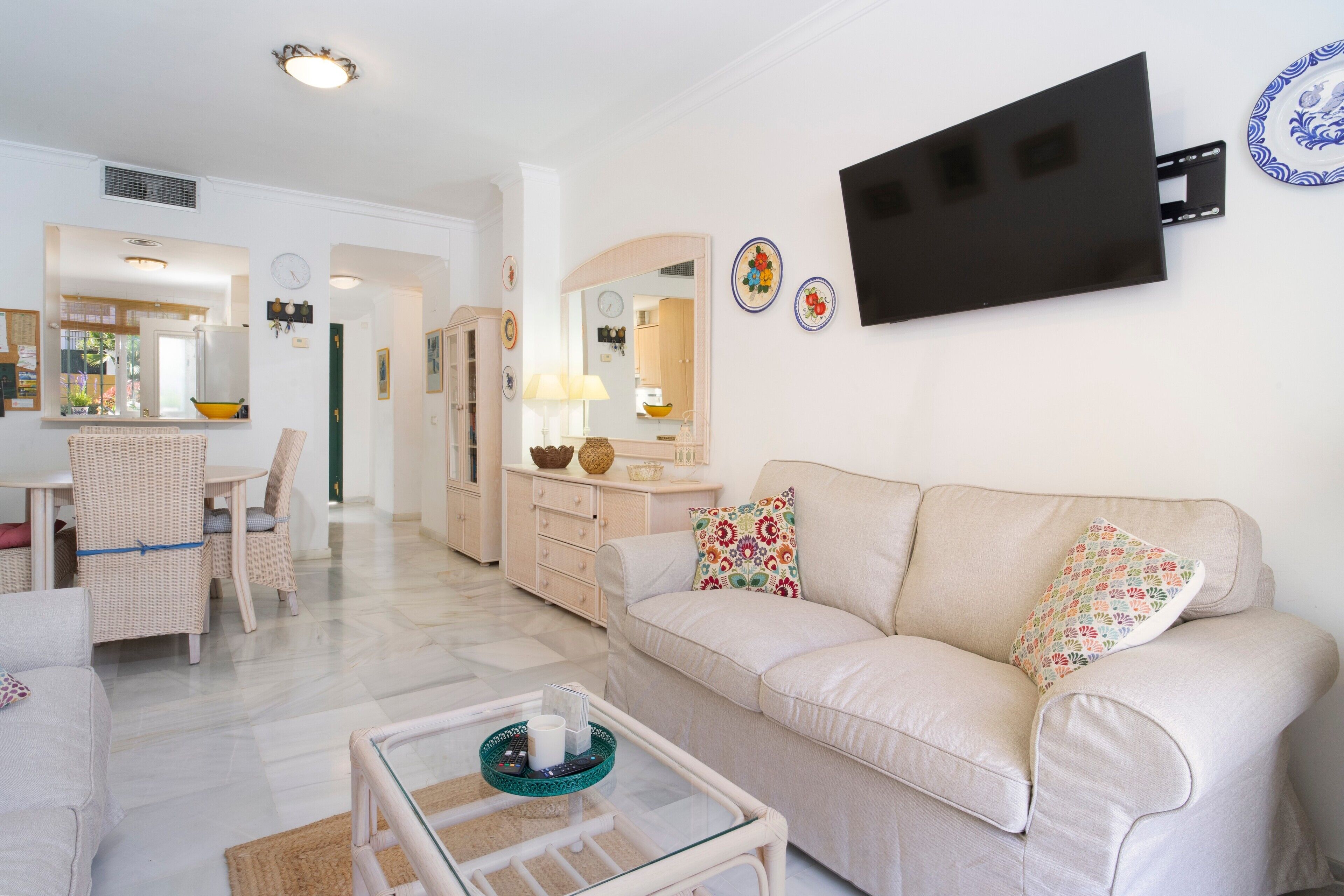 Ein Wohnzimmer mit einer Couch, einem Couchtisch und einem an der Wand befestigten Fernseher.