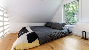 Una habitación pequeña con cama, ventana y pared blanca.