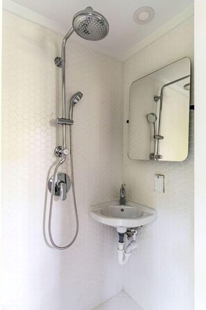 Un baño con ducha, lavamanos y espejo.