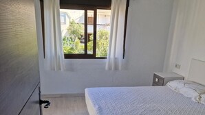 Una camera da letto con un letto, una finestra con tende, un condizionatore d'aria e un comodino.