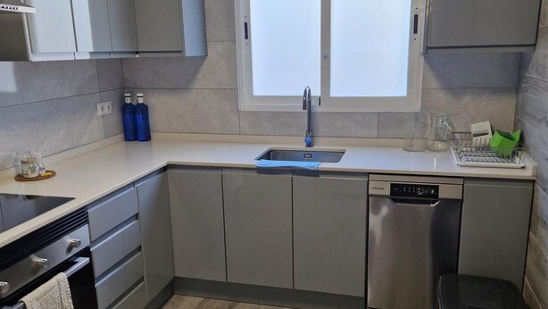 Una cucina moderna con mobili grigi, una lavastoviglie e una finestra sopra il lavello.