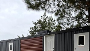A portable building with a bench, wooden steps, and a door labeled 'Willow Tent.'