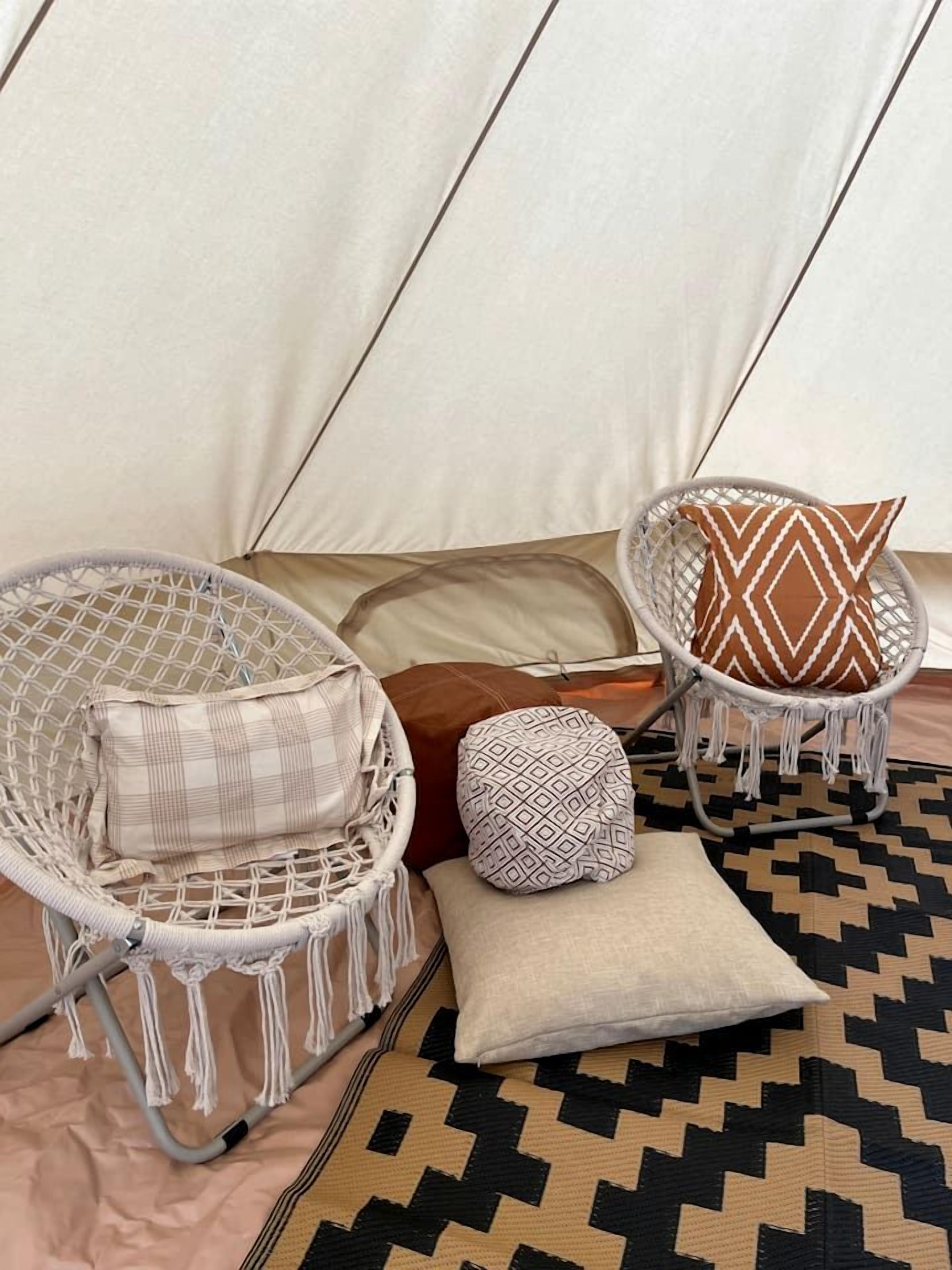 A cozy seating area with two wicker chairs, a patterned cushion, and a woven rug.