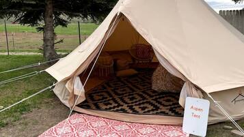Une tente portant l’inscription « Aspen Tent », avec un tapis à motifs placé à l’extérieur.