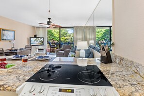 Eine moderne Küche mit Einbauherd, Essbereich mit Tisch und Stühlen sowie Wohnbereich mit Sofa und Fernseher.