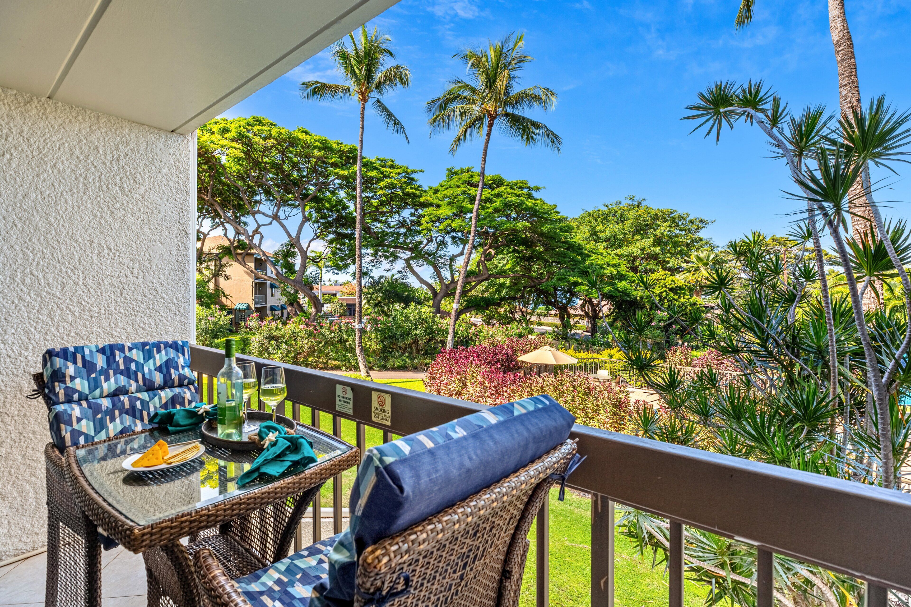 A balcony with wicker furniture, a glass table, and a bottle of water.