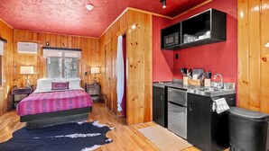 Una habitación con una cama, un pequeño kitchenette y una ventana.