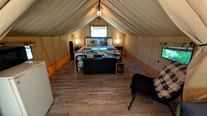 Ein Zelt mit Bett, Stuhl, Fernseher und Kühlschrank.