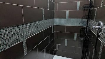 A modern bathroom with dark tiles, a shower area, and a tiled floor.