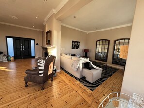 A spacious living room with a fireplace, a zebra-patterned armchair, a white sofa, and a large mirror. - Luxury one bedroom apartment in Green Point with AC, a pool and a view. (Cape Town)