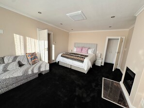 A bedroom with a bed, a sofa, a fireplace, and a door. - Luxury one bedroom apartment in Green Point with AC, a pool and a view. (Cape Town)