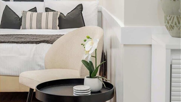 Ein modernes Schlafzimmer mit Bett, Nachttisch und Fenster.