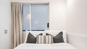 Ein Hotelzimmer mit Bett, einem Vorhangfenster und Blick nach draußen.