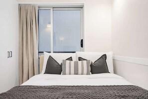 A hotel room with a bed, a window with curtains, and a view of the outside. - LaneStay - Cosy CBD Studio Near Southern Cross (Melbourne)