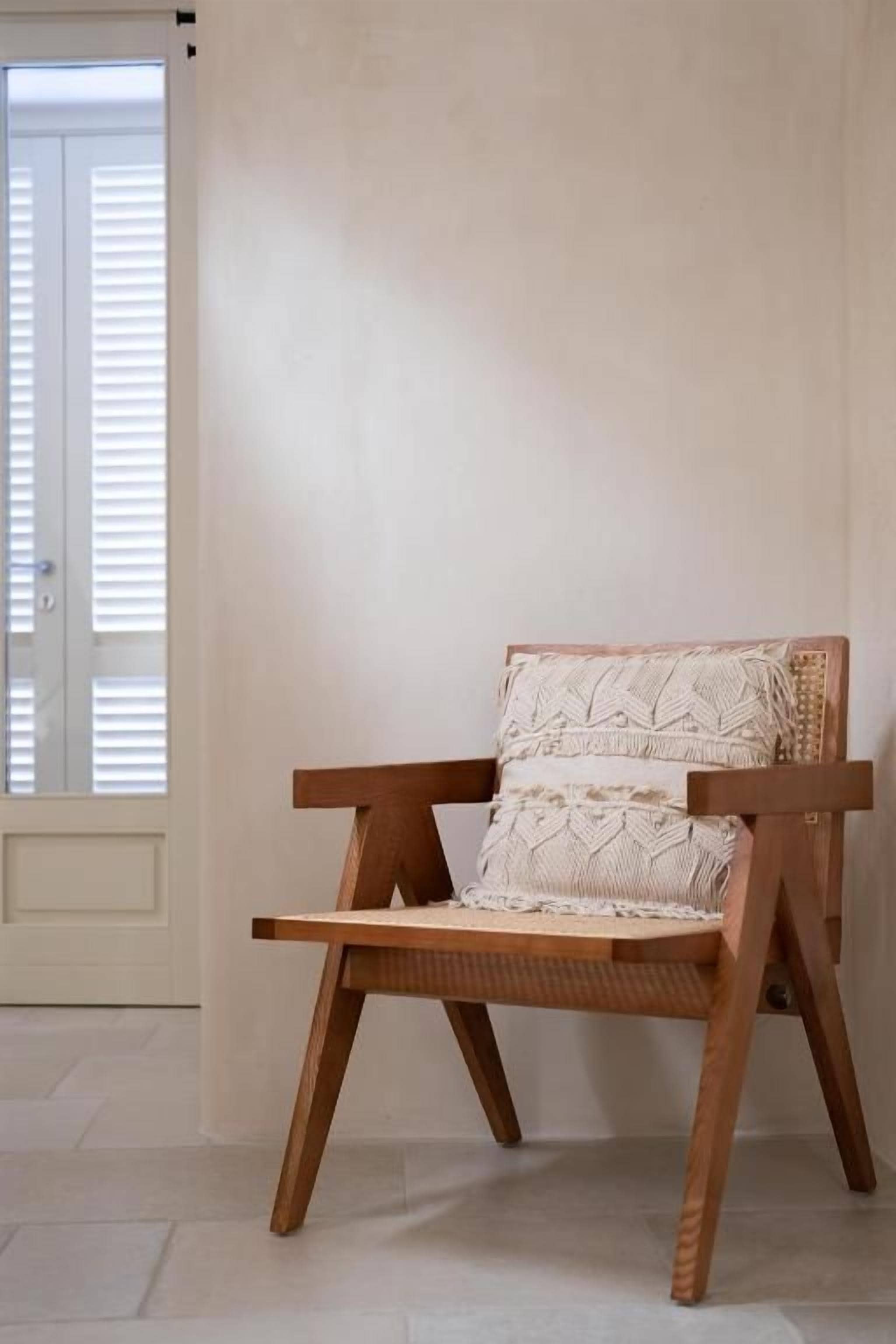 A wooden chair with a woven seat and backrest, positioned against a plain wall.