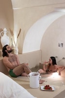 Una coppia si rilassa in una vasca da bagno, con un boccale bianco e fragole su un piatto.