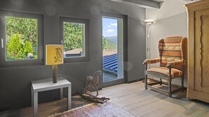 Um quarto com uma janela grande, uma cadeira, um abajur e um armário.