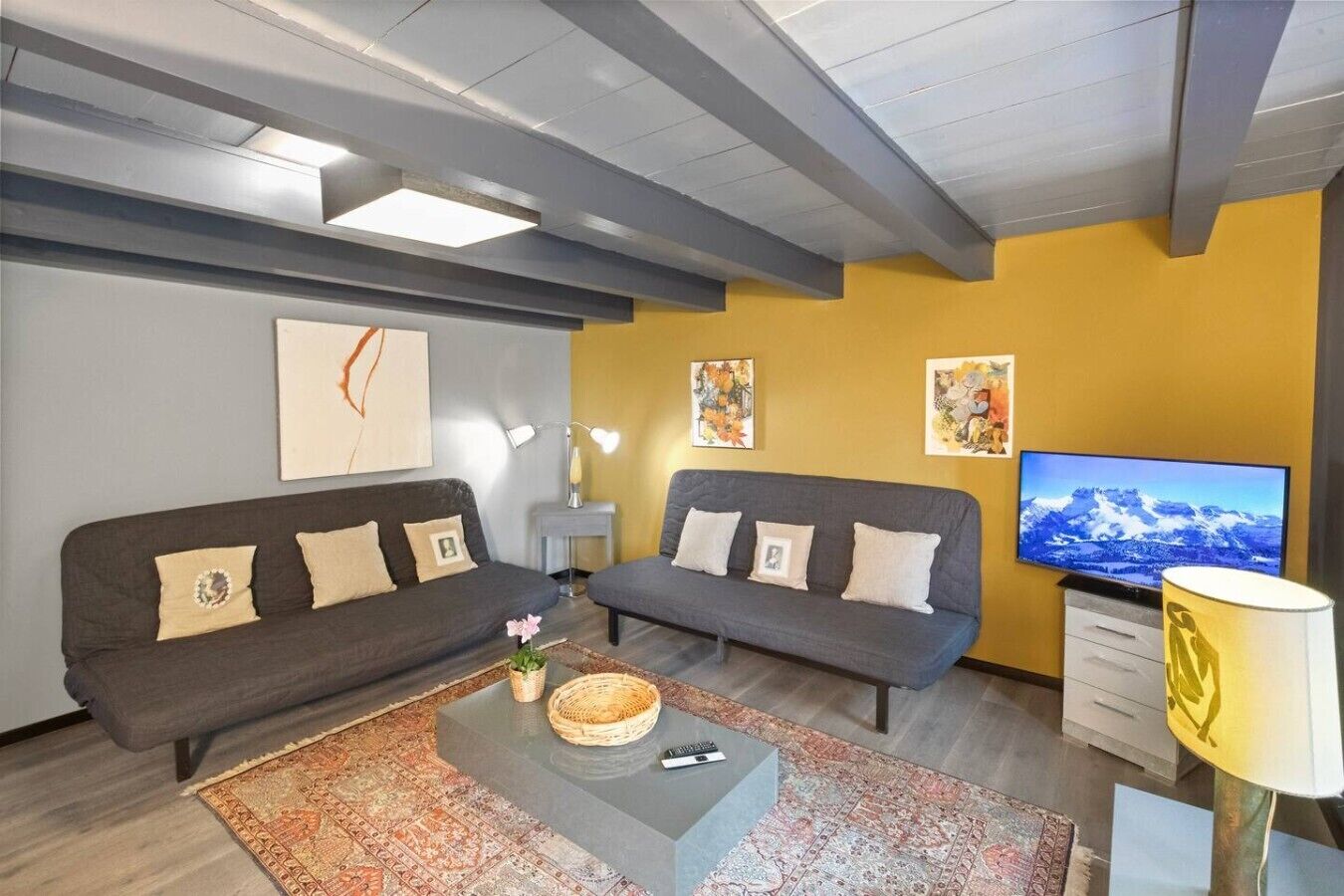 A living room with two sofas, a coffee table, a TV, and artwork on the walls.