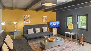 Uma sala de estar moderna com sofá, televisão de tela plana, luminária e obras de arte nas paredes.