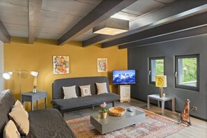 A modern living room with a sofa, a flat-screen TV, a lamp, and artwork on the walls. - A little slice of paradise for animal lovers (Morgins)