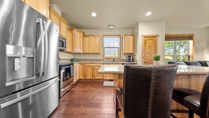 Una cocina con armarios de madera, electrodomésticos de acero inoxidable y una zona de comedor con banco.