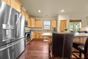 Una cocina con armarios de madera, electrodomésticos de acero inoxidable y una zona de comedor con banco.
